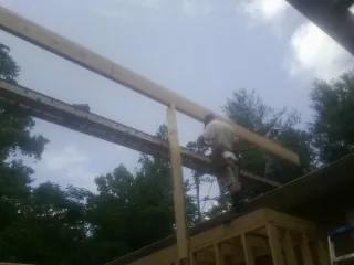 Carpenter setting a ridge beam over a new addition frame — Ice Dam Removal by Roofing Brothers in Nesconset