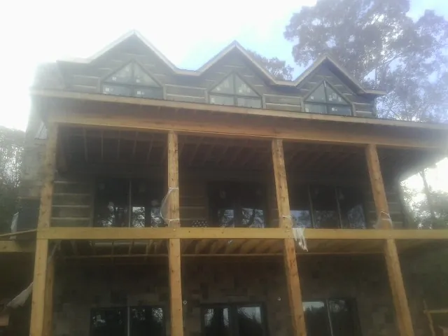 Dormers and porch framing on a large log home under construction — Roof Coating work by our crew in Nesconset