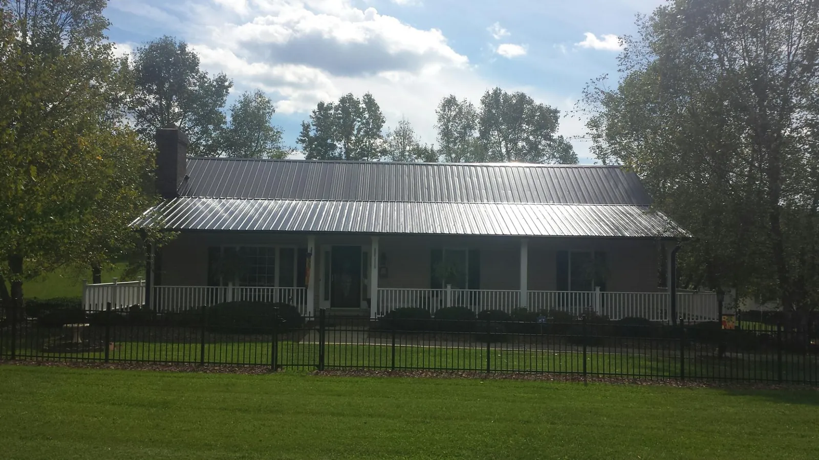 Gray metal roof on a brick ranch with a full width front porch — Gutter Guard Installation work by our crew in Nesconset