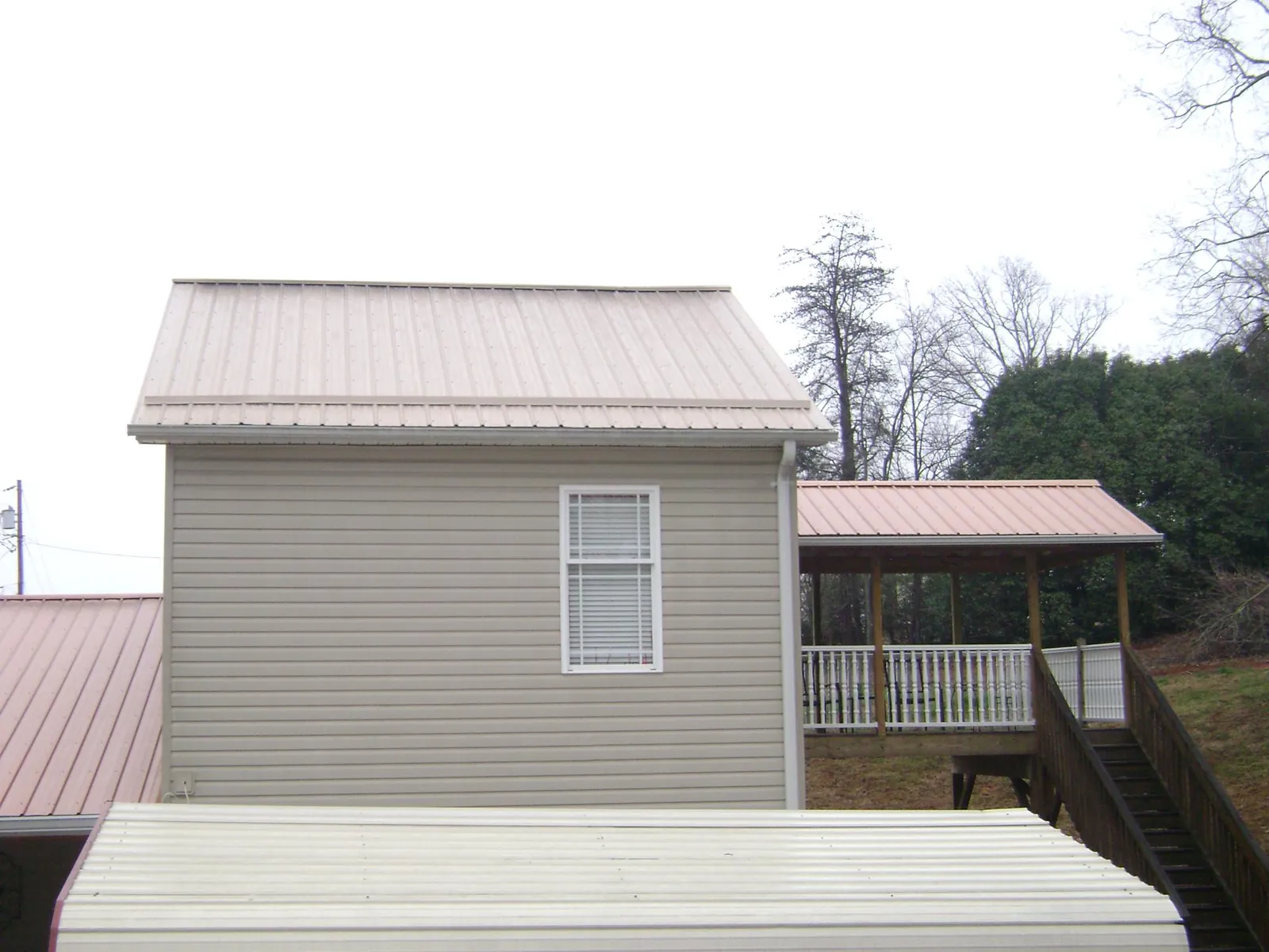 Tan metal roofs on a two story addition and attached porch, from a Roof Replacement job in Nesconset